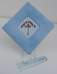 easel for small needlepoint made from drapery hook by Sue Dulles